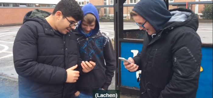 Drei Jugendliche schauen auf ihre Handys und lachen höhnisch